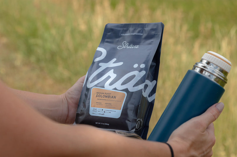 Bag of coffee beans and blue thermos with nature background